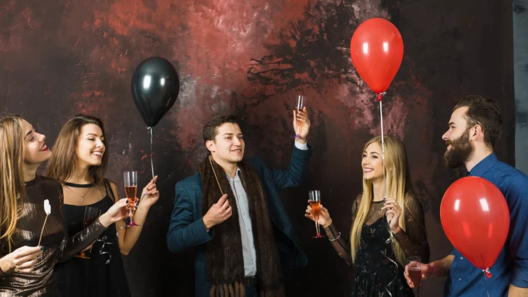 Group of friends holding balloons and glasses of champagne, smiling and celebrating indoors, representing Planning a Party in West Des Moines