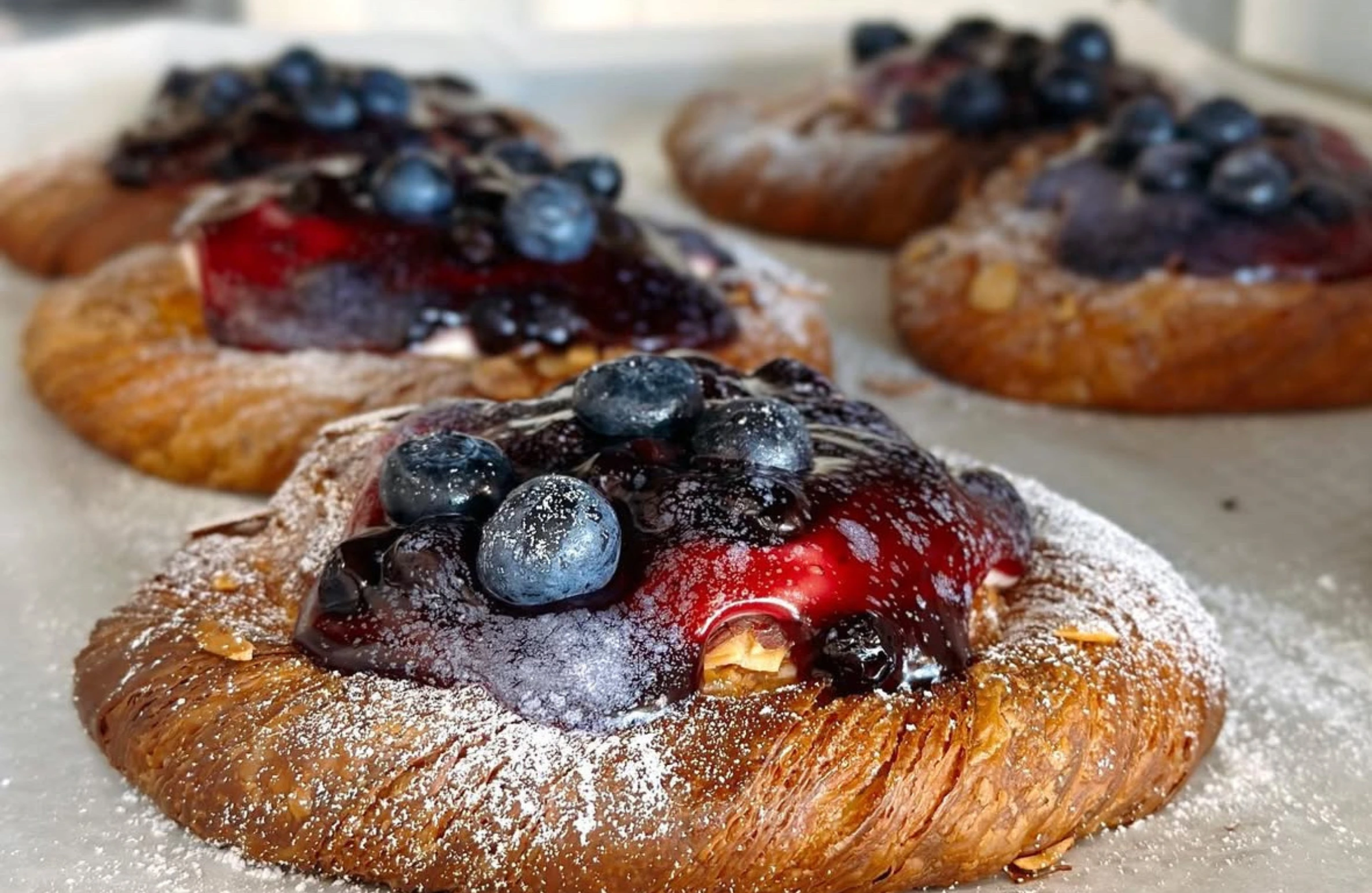Freshly baked pastries topped with blueberries and berry glaze, dusted with powdered sugar — Top 7 Desserts in Iowa You Can Order Online.
