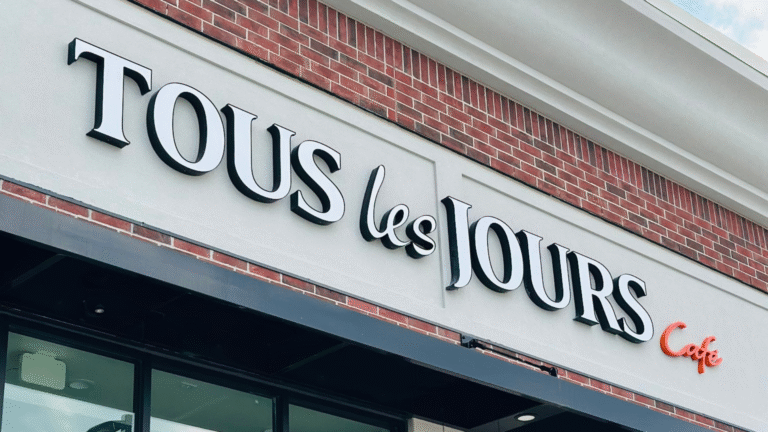 Exterior storefront sign of TOUS les JOURS Café in Iowa, a neighborhood favorite and winner of the Best of the West Award.