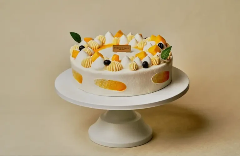 Best TOUS les JOURS Items to Order on DoorDash : Colorful mango cream cake on a stand from TOUS les JOURS, showcasing fresh bakery items available on DoorDash in West Des Moines