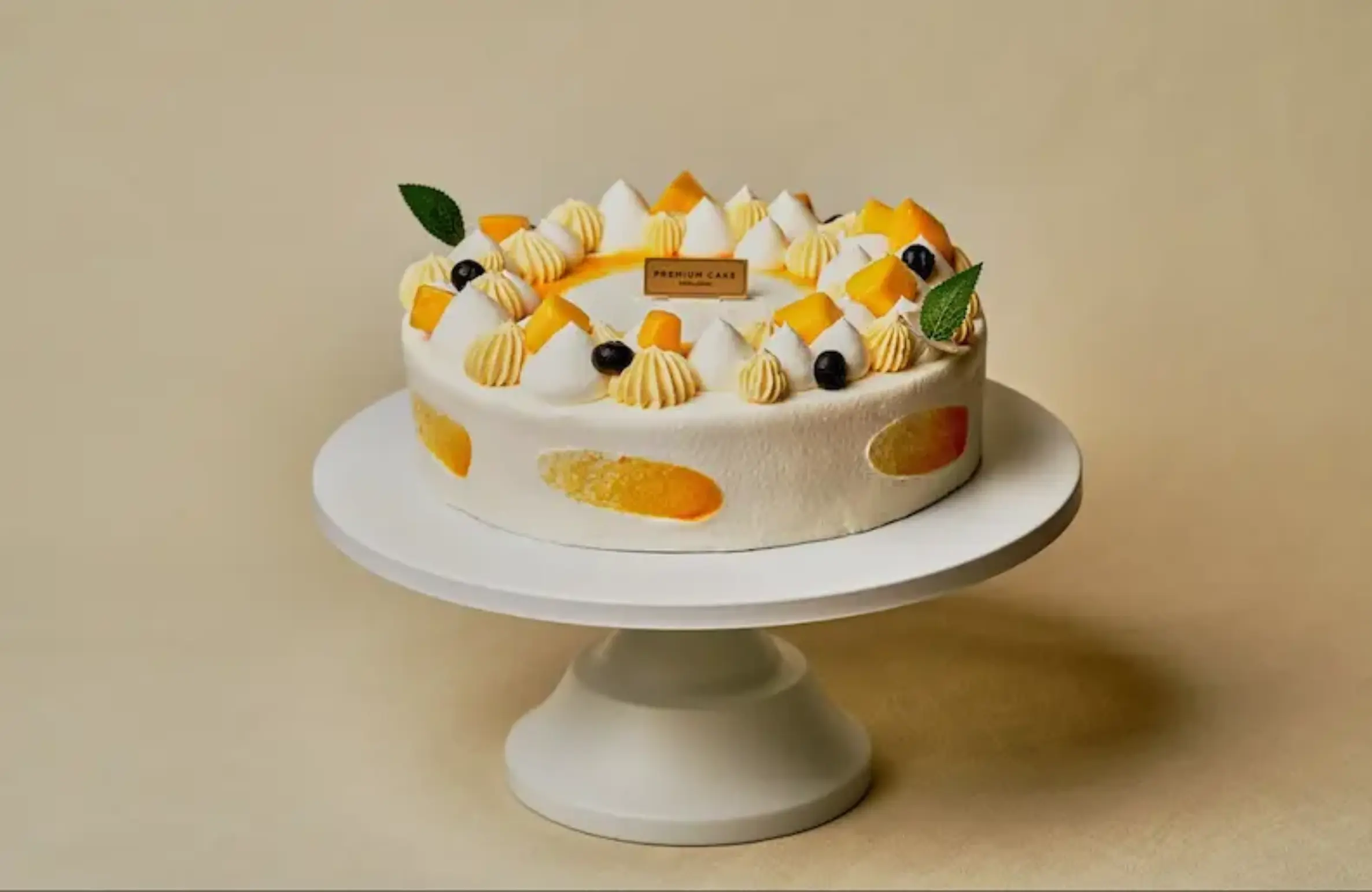 Colorful mango cream cake on a stand from TOUS les JOURS, showcasing fresh bakery items available on DoorDash in West Des Moines